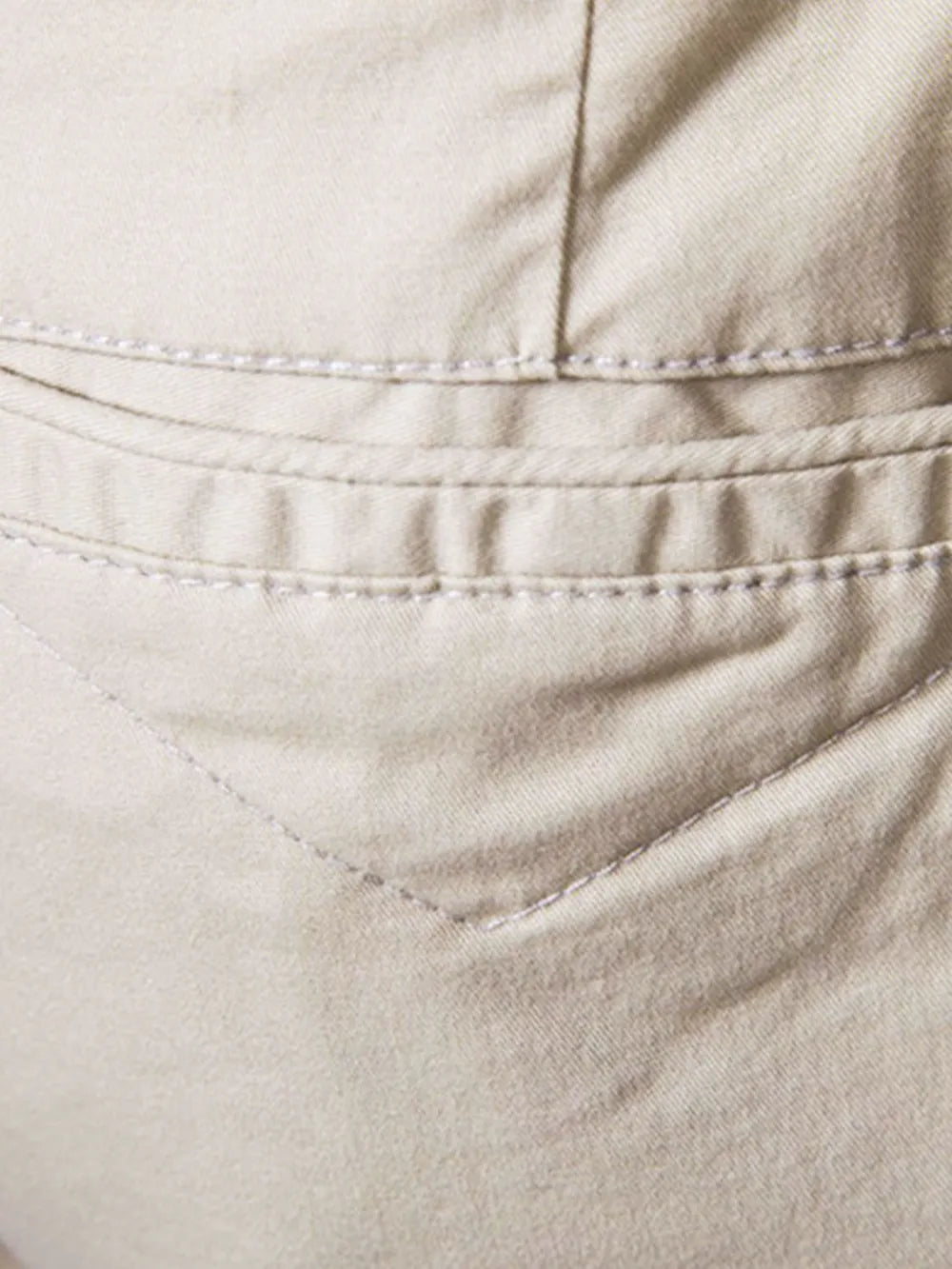 Close-up of comfortable bermuda shorts with pockets in beige fabric by Trendsi showing stitching details